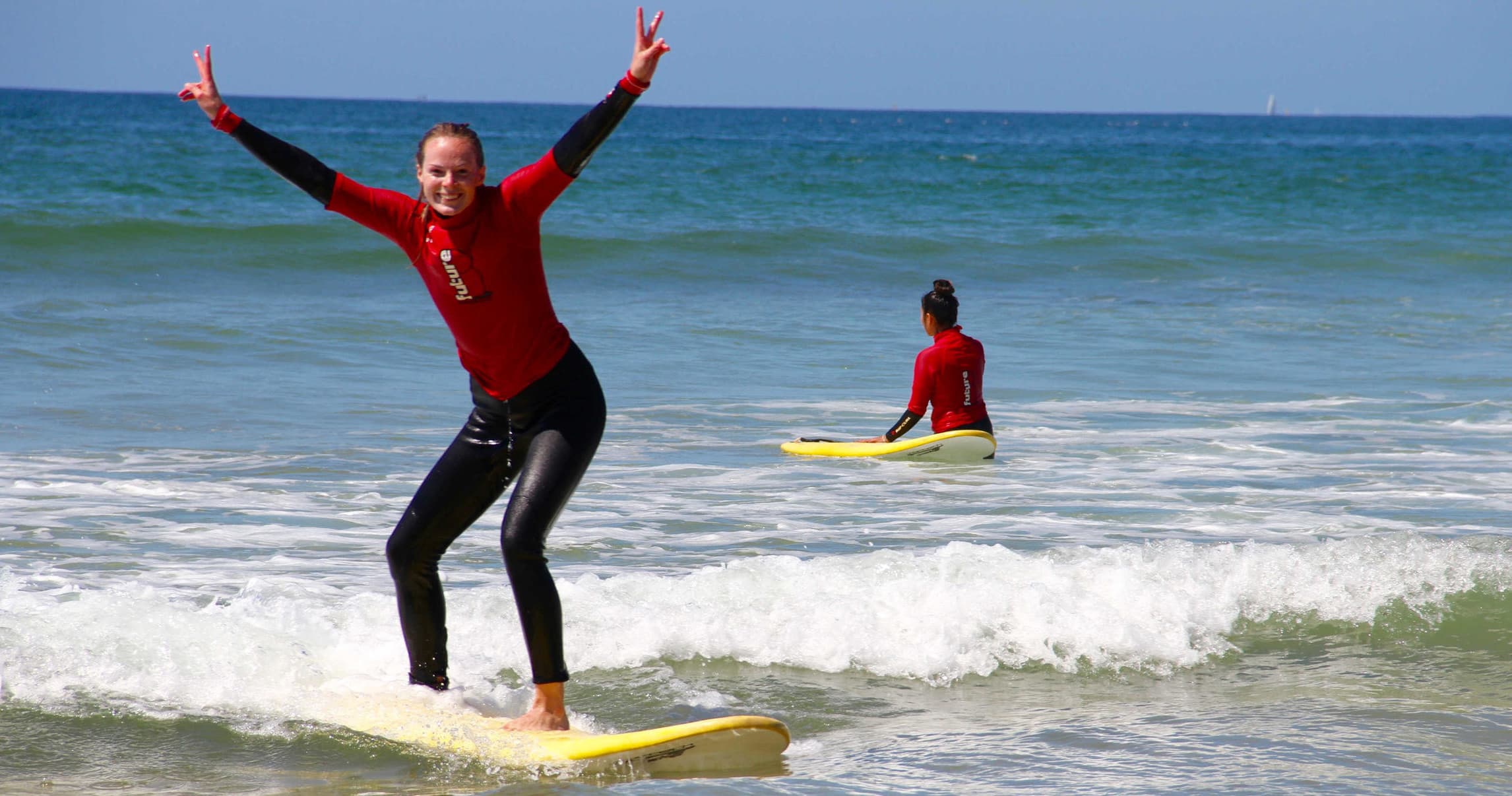 Surfer celebrating standing on yellow board in shallow surf
