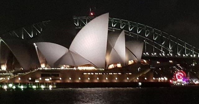 Nighttime Sydney Opera House lit on harbor for scenic evening cruise