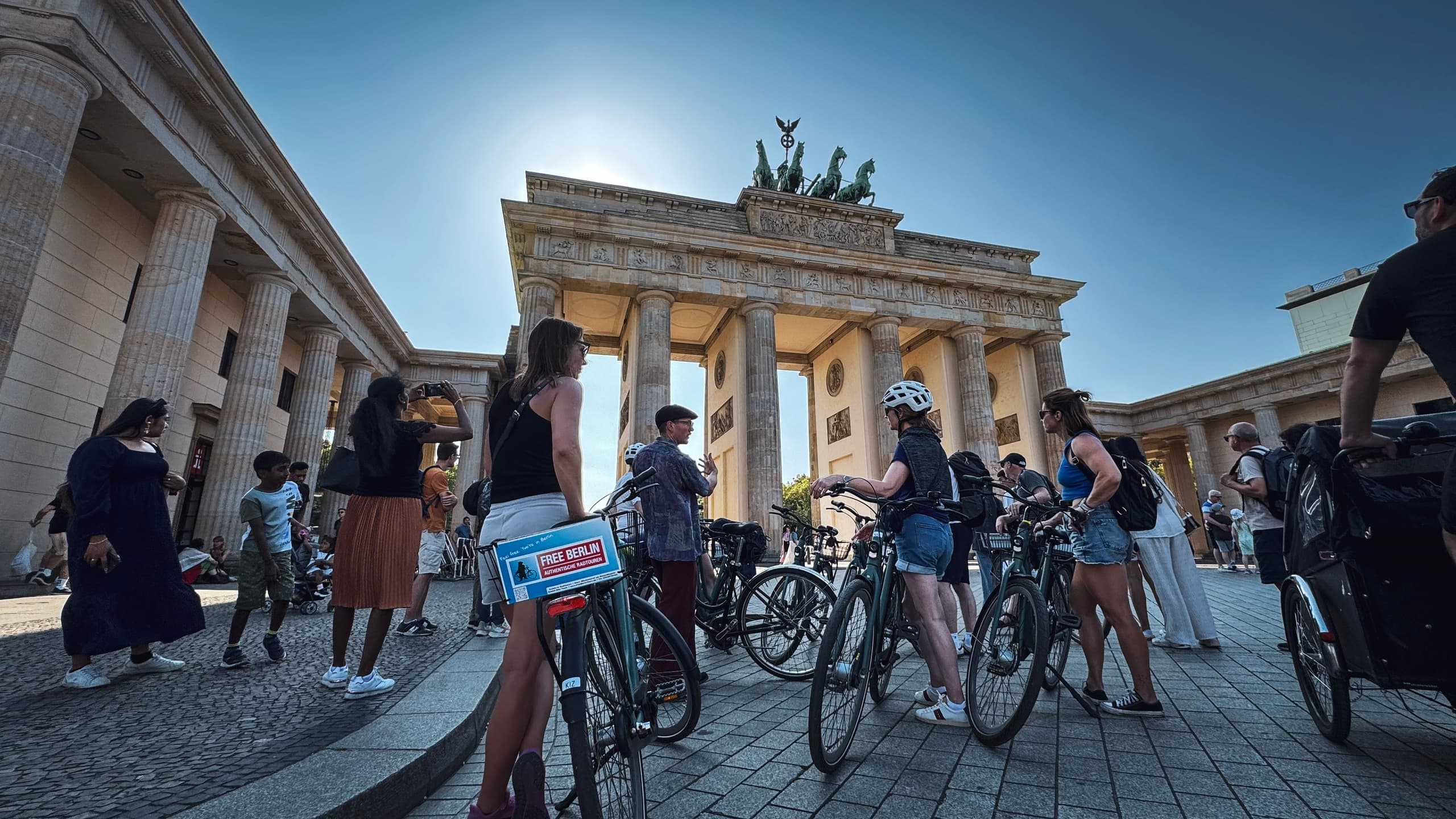 Wide view of cyclists at Brandenburg Gate in a sunny Berlin tour