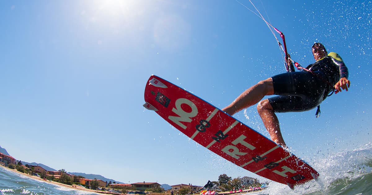 Kiteboarder jumping above waves with sunny sky background