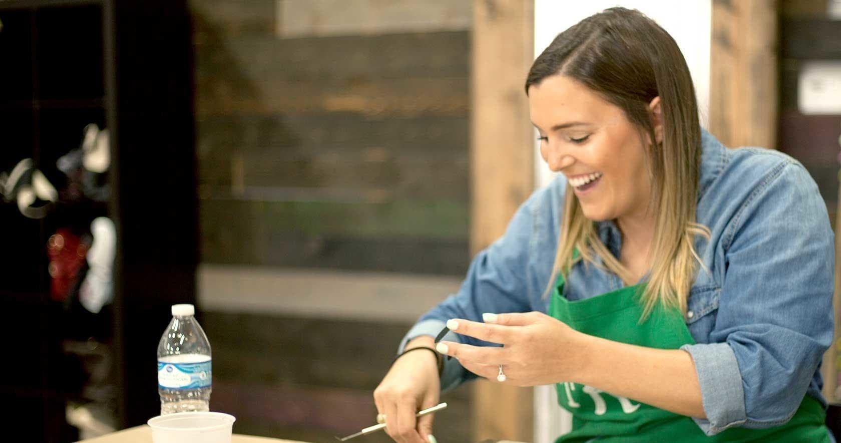 Woman painting a wooden sign at an indoor craft workshop