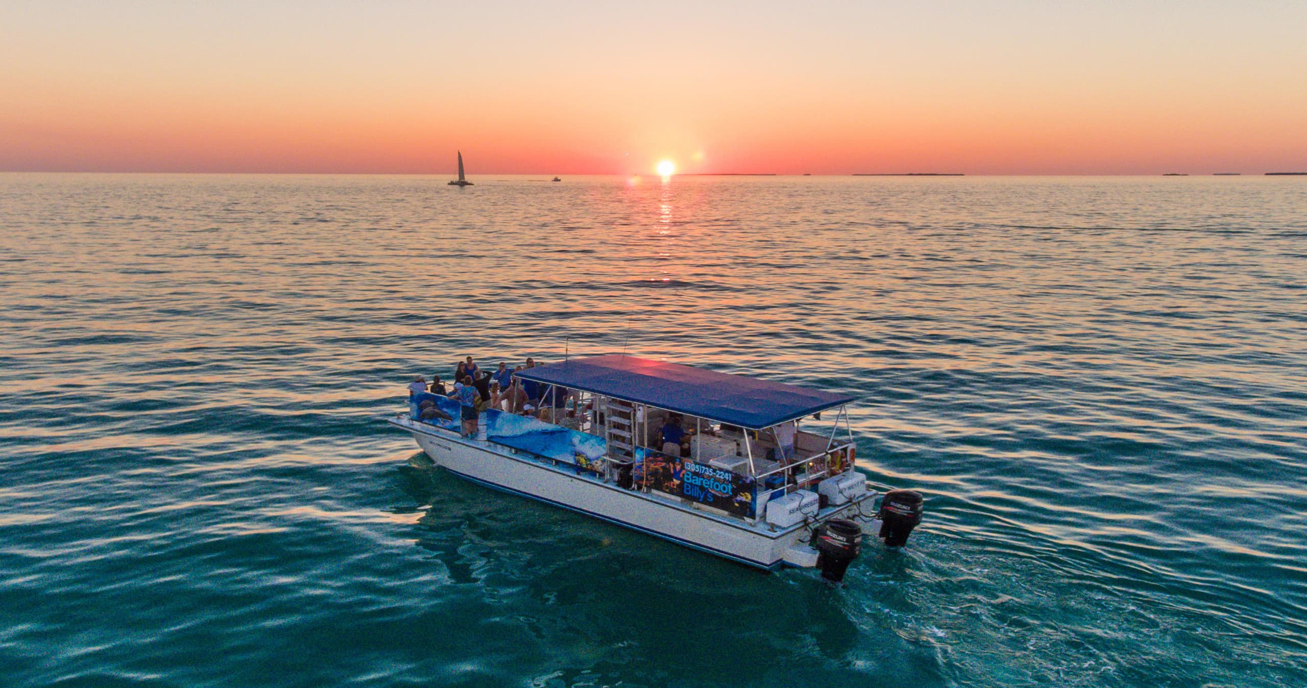 Tour boat cruising at sunset over tranquil tropical waters
