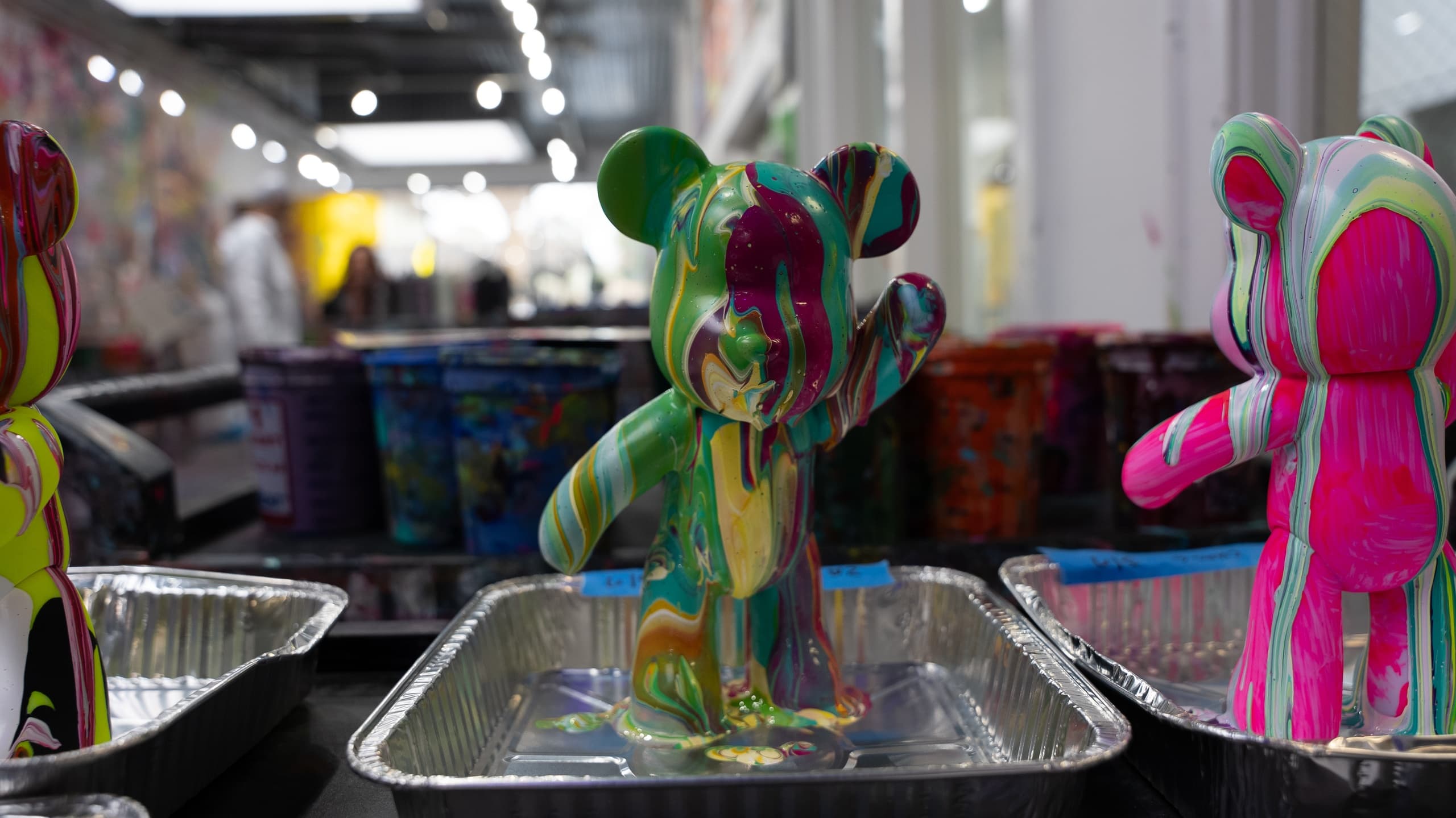 Paint-covered designer toys drying on trays in art studio