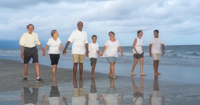 Extended family walking along reflective shoreline at blue hour
