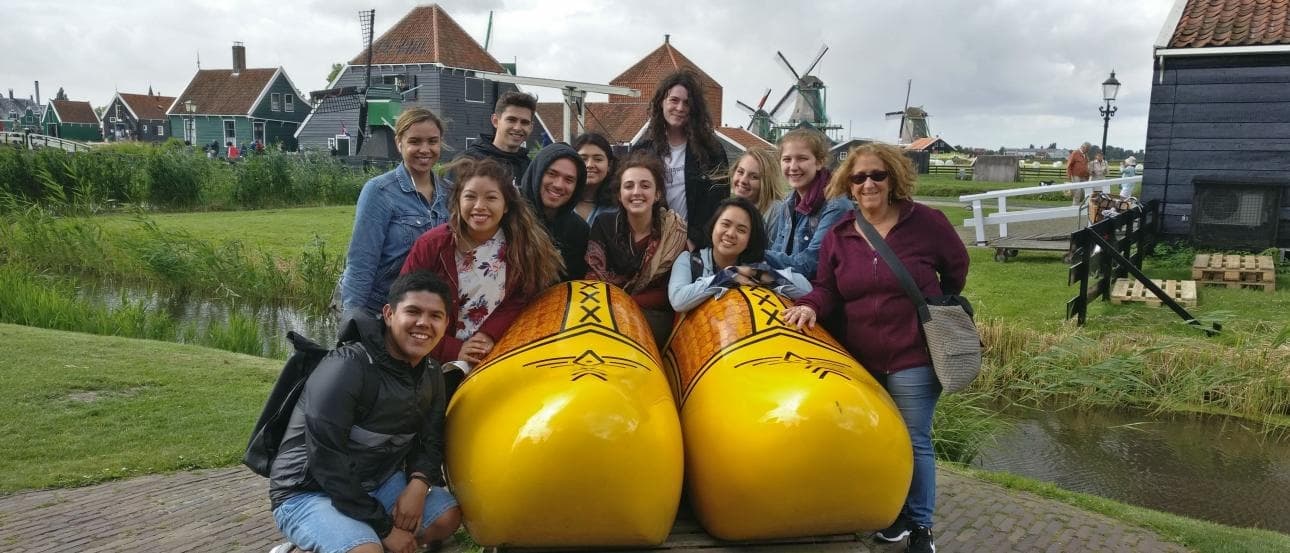 Group posing with yellow kayaks near Dutch windmills and canal