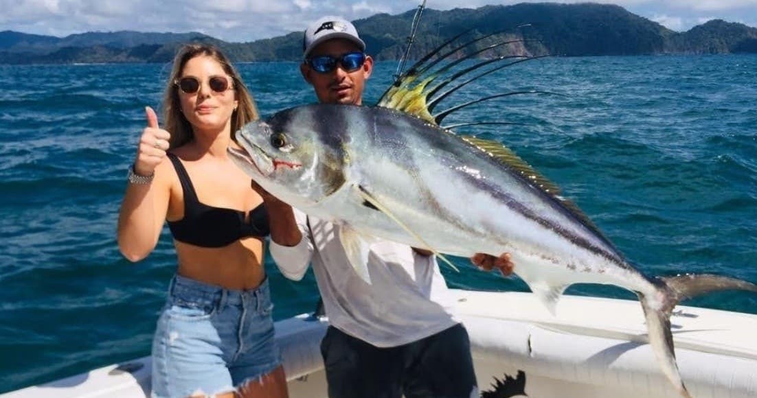 Anglers posing with large roosterfish on sportfishing boat off coast