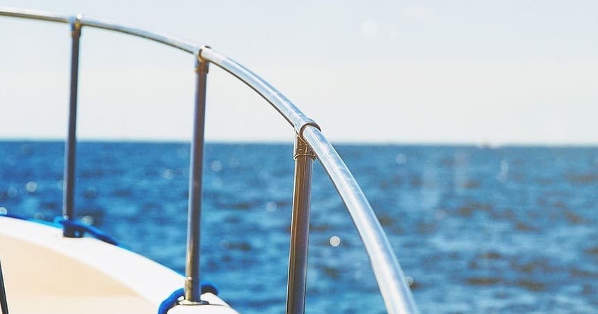 Boat bow and railing over open ocean, day sailing on blue sea