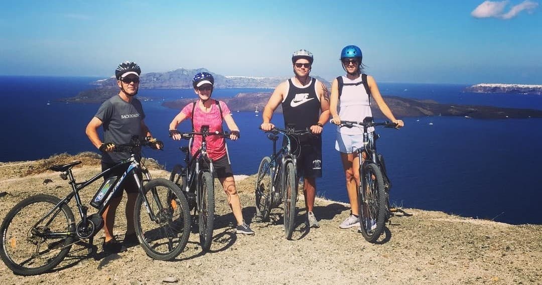 Group e-bike tour cycling along Santorini cliffside with sea views