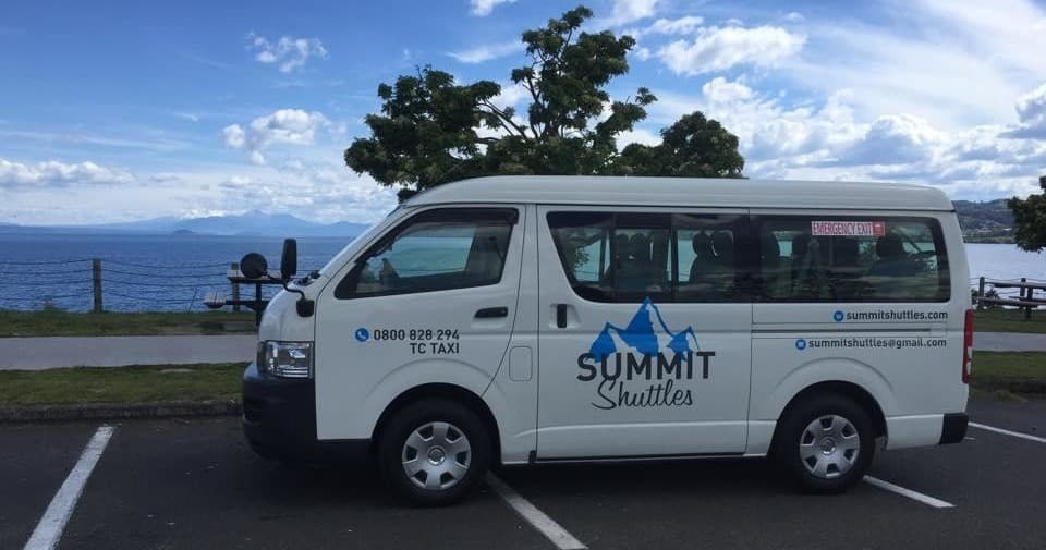 Shuttle van parked by lakeside overlooking water and sky