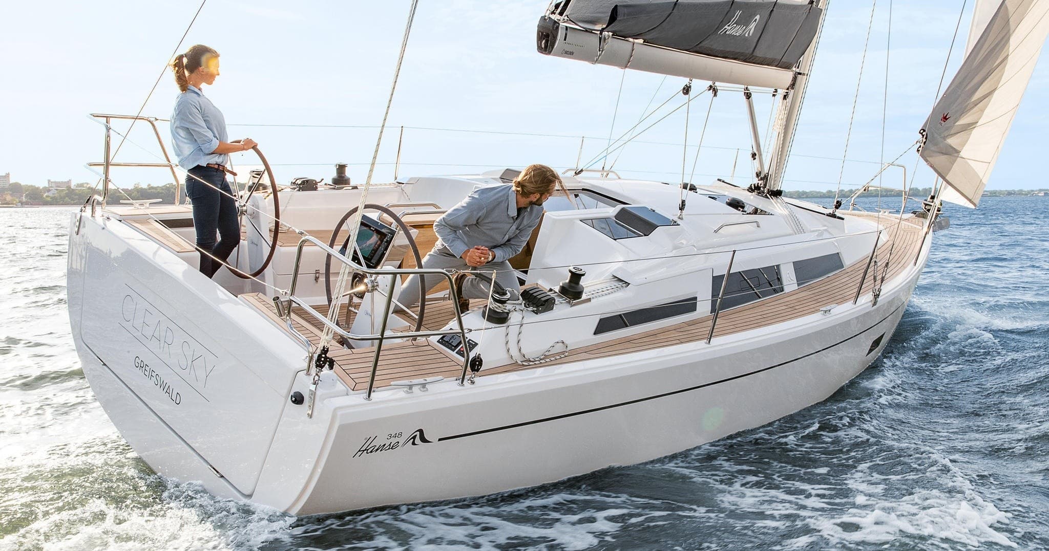 Sailors cruising a white sailboat on open ocean near islands