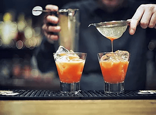 Bartender pouring cocktails at dimly lit cocktail bar