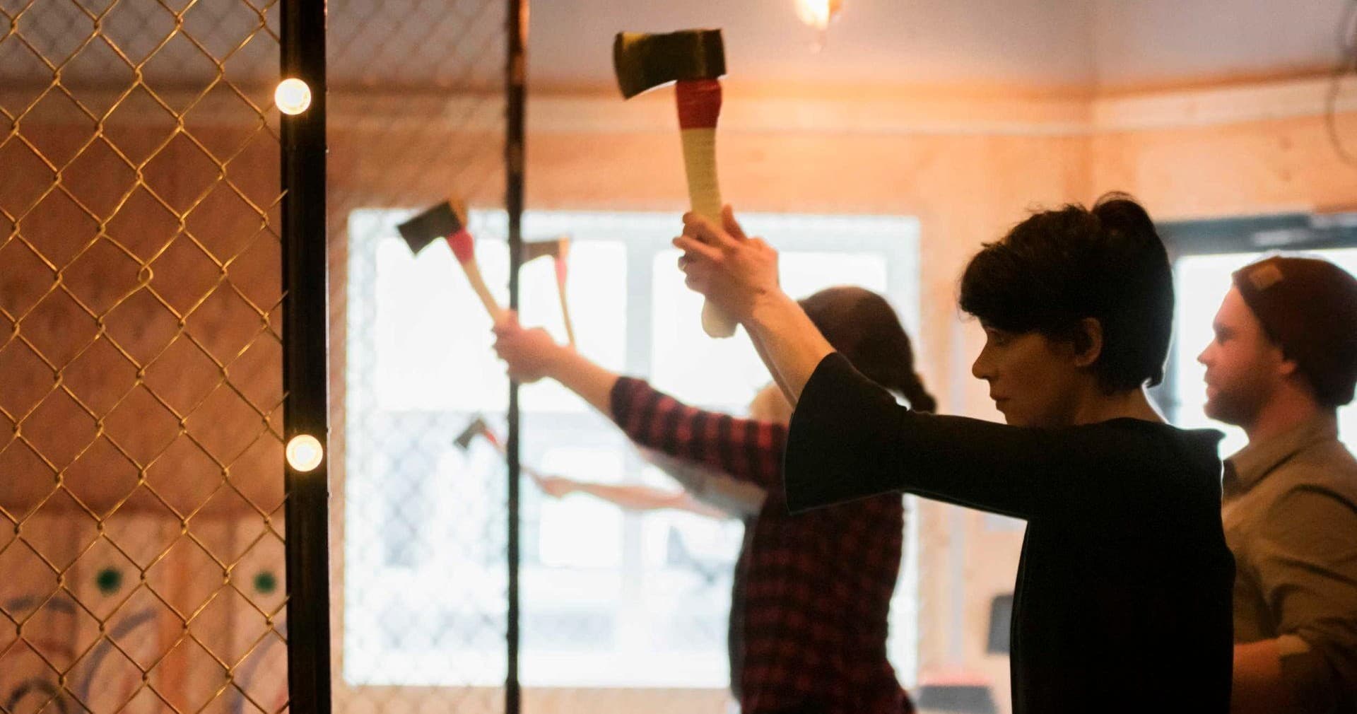 Group axe throwing lesson indoors with participants throwing