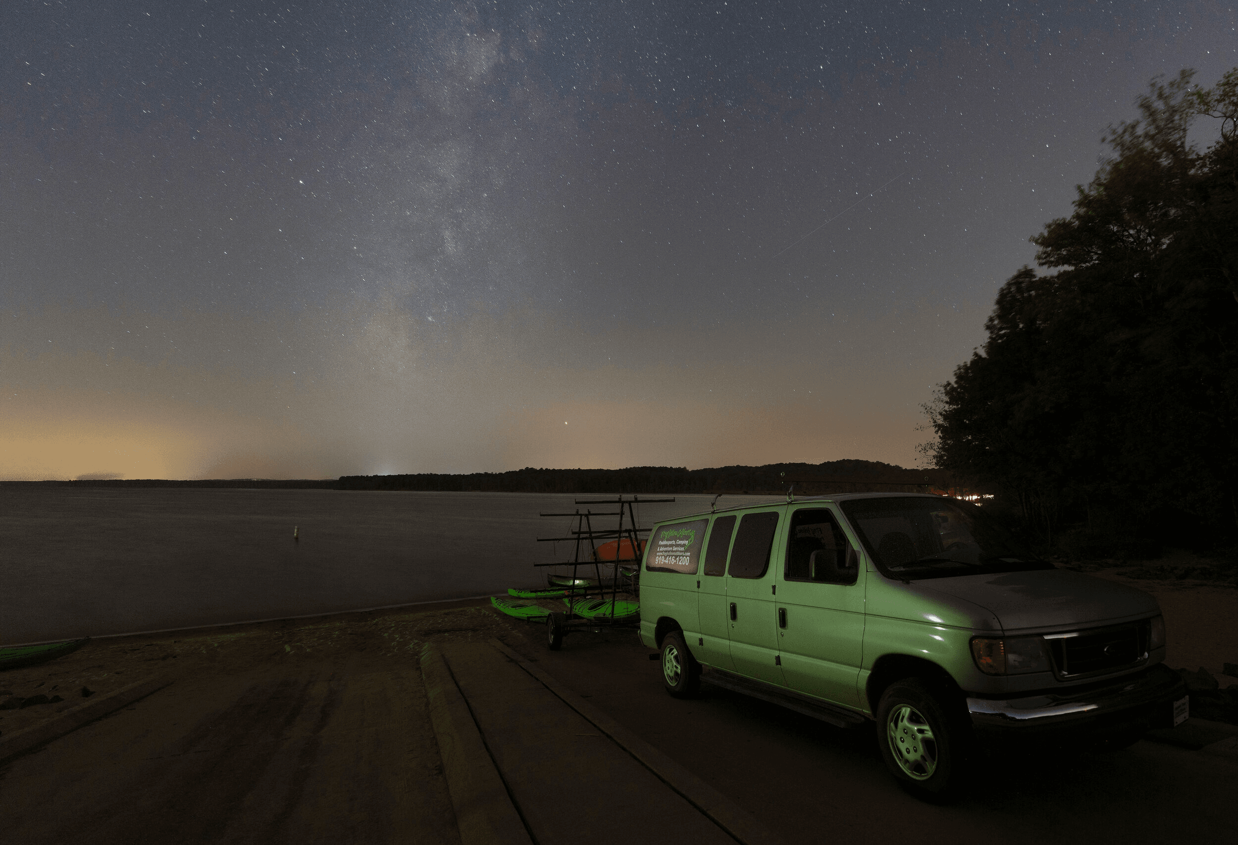 Van at lakeside launch under Milky Way night sky panorama