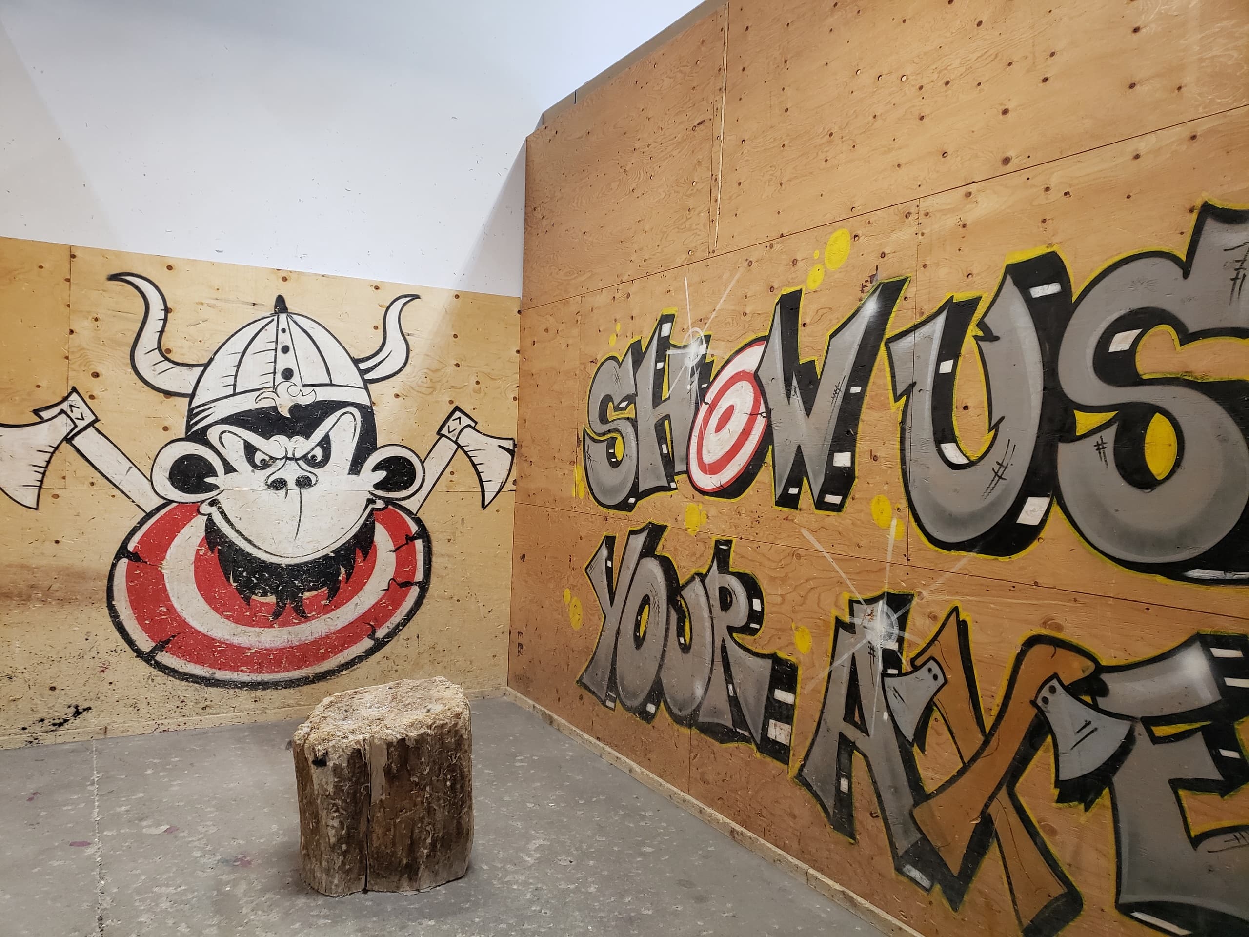 Indoor axe-throwing lane with stump and graffiti mural, Edmonton
