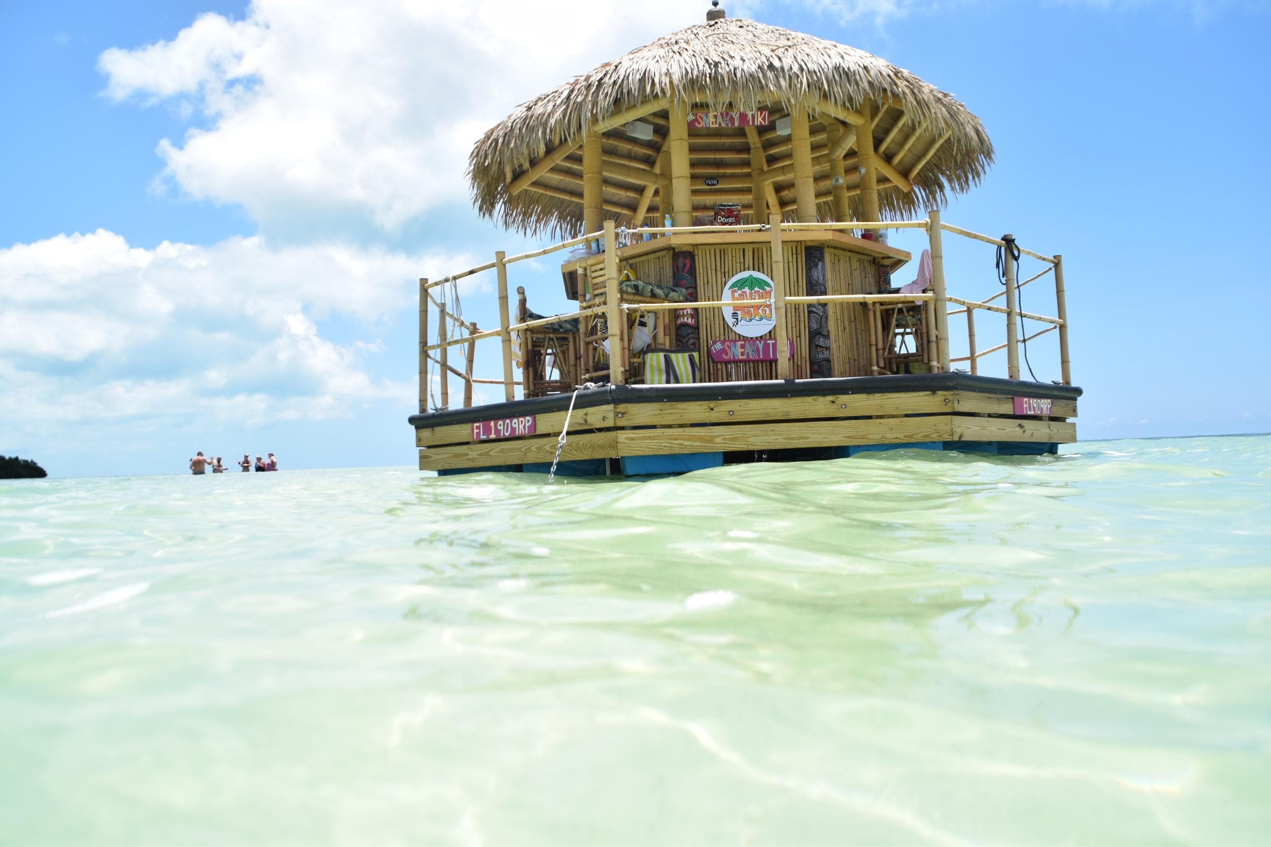 Thatched tiki bar raft floating in crystal clear shallow Caribbean water