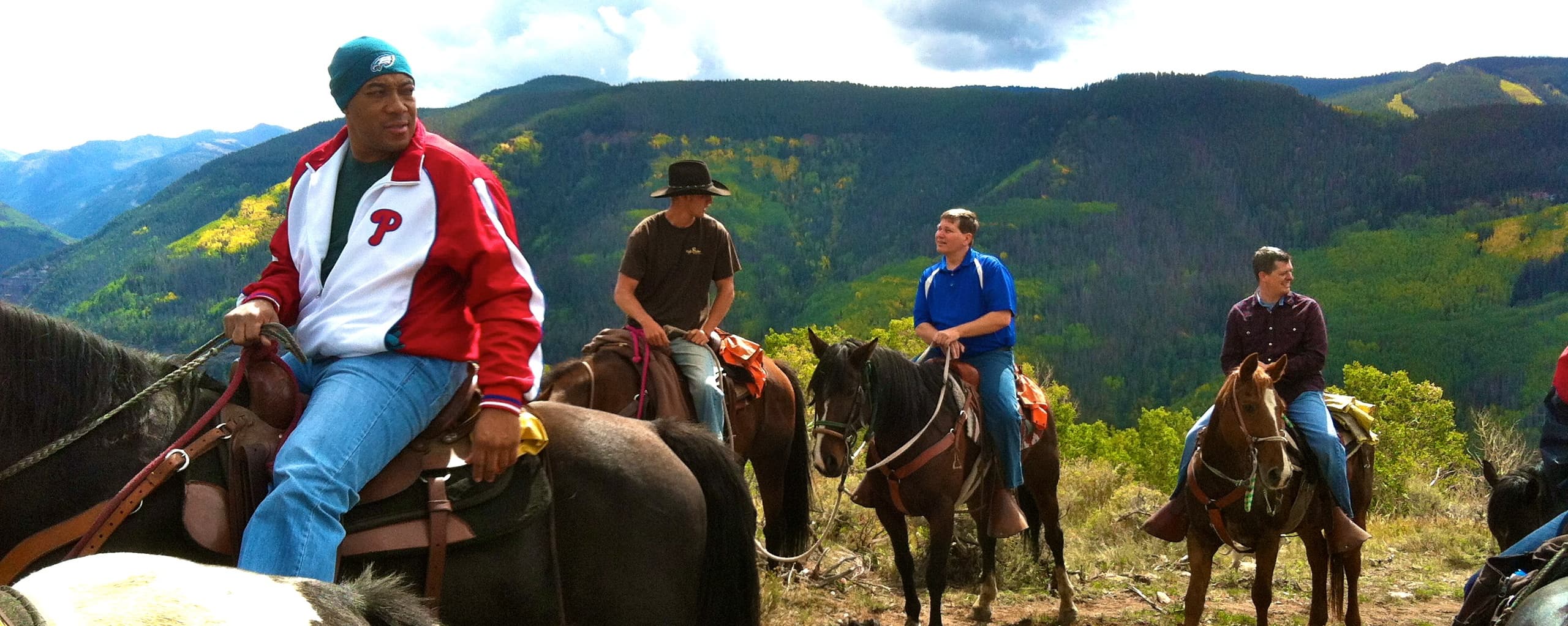 Group horseback trail ride across panoramic mountain ridge