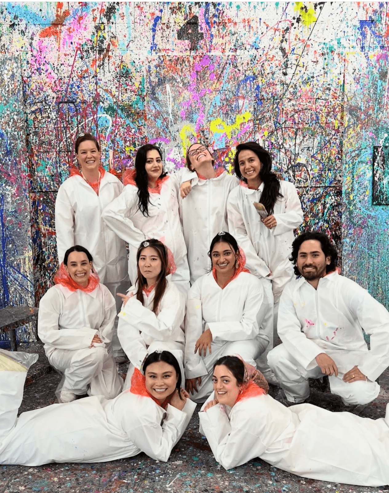 Group in protective suits posing in indoor splatter paint studio experience