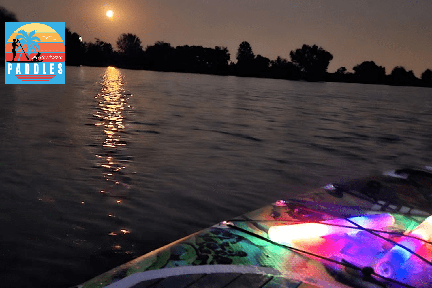 Night kayaking with colorful deck lights gliding at dusk