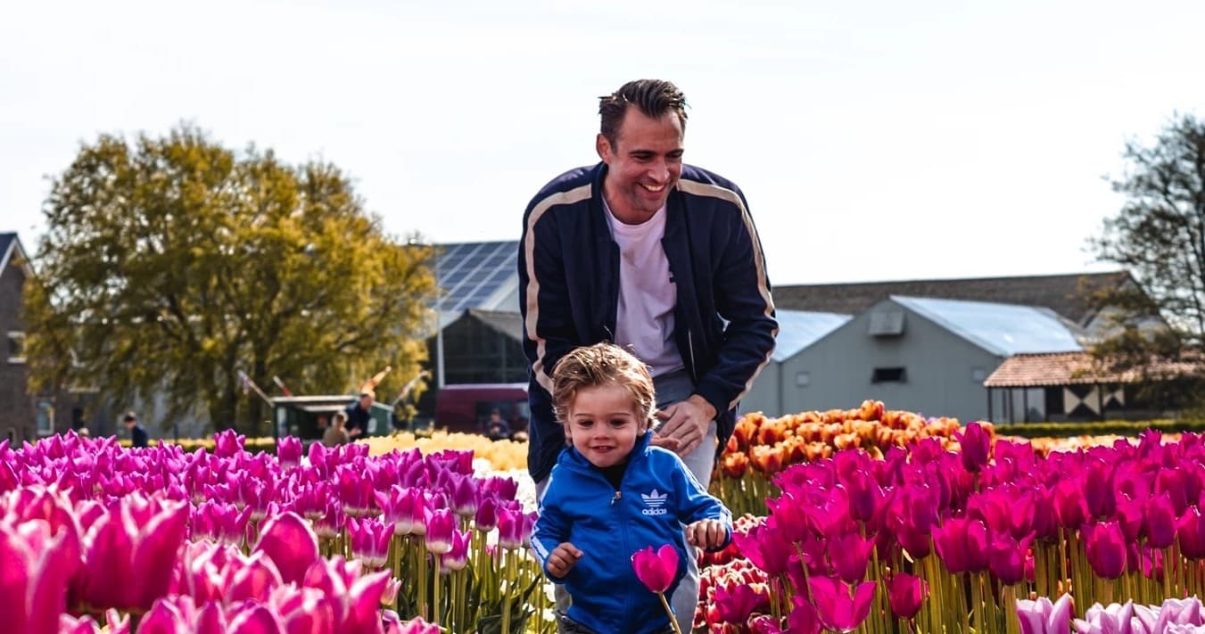 Father and child running through colorful tulip fields outdoors