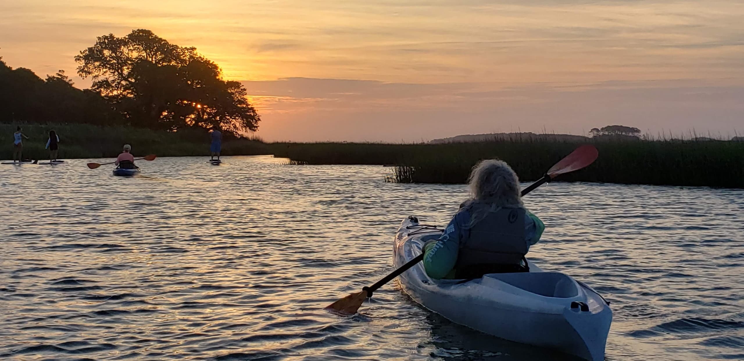 Kayaker paddling at sunset on tranquil estuary water
