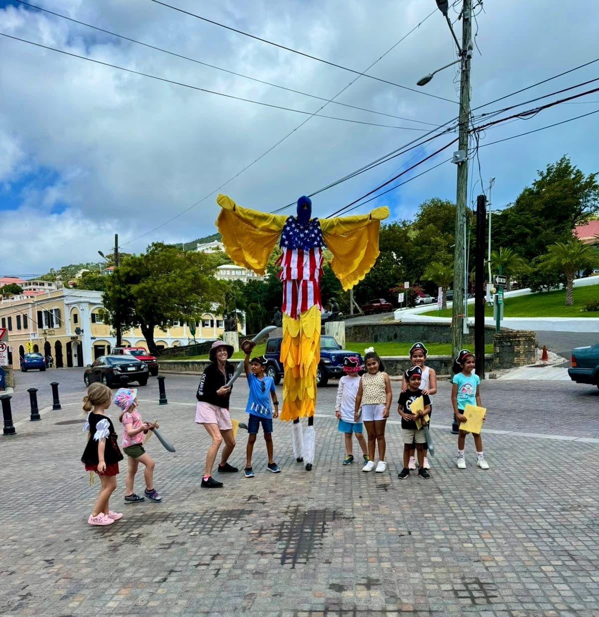 Stilt street performer in colorful costume entertaining kids in harbor square
