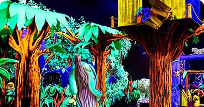 Blacklight mini golf course with neon trees in indoor arcade