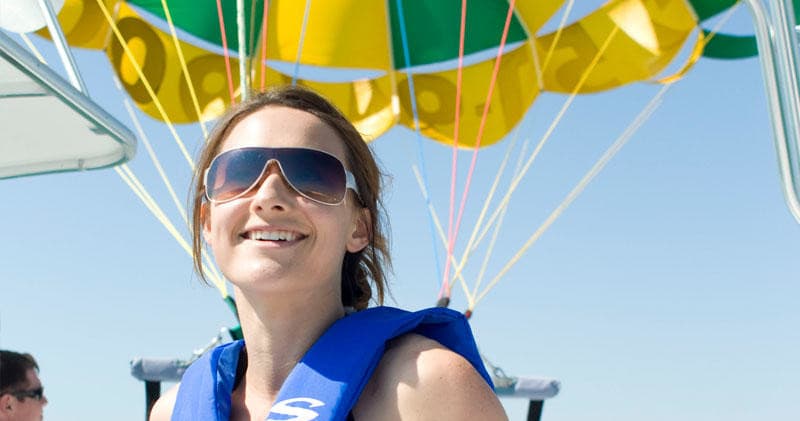 Smiling passenger wearing life vest on parasail boat deck