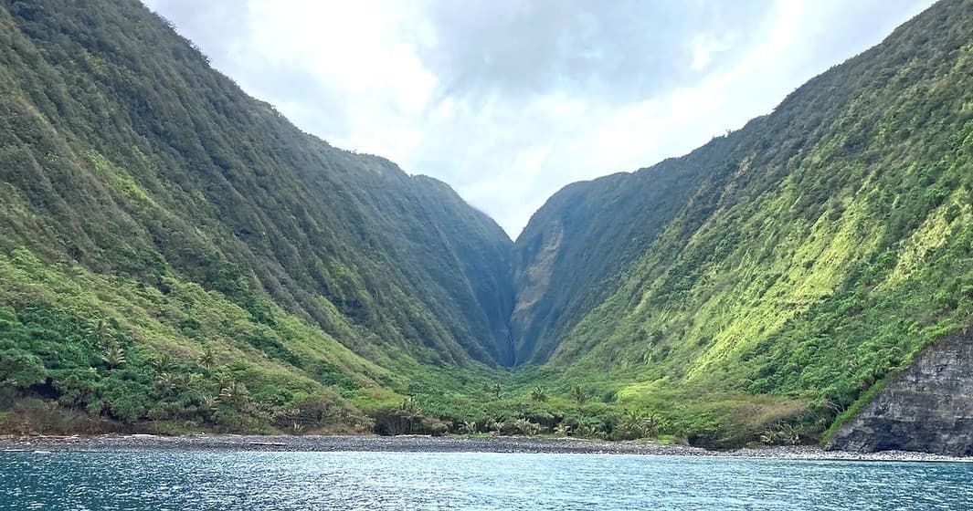 Dramatic green volcanic valley opening to ocean, coastal vista