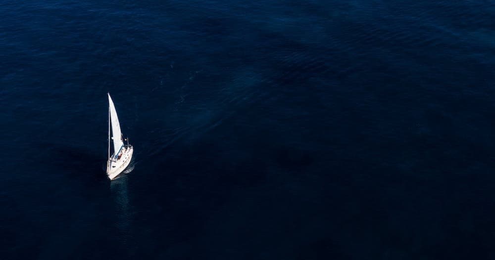 Aerial view of lone sailboat navigating deep open ocean waters