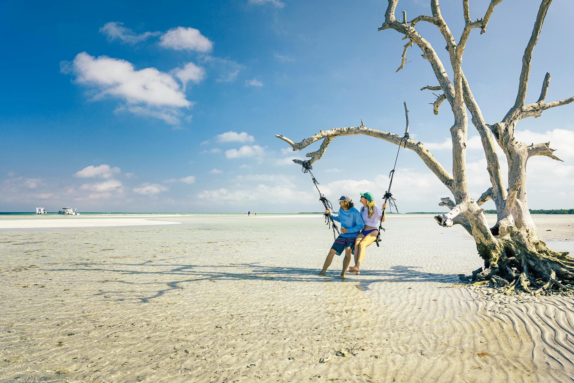 Beachgoer on driftwood swing at sandy Key West shoreline