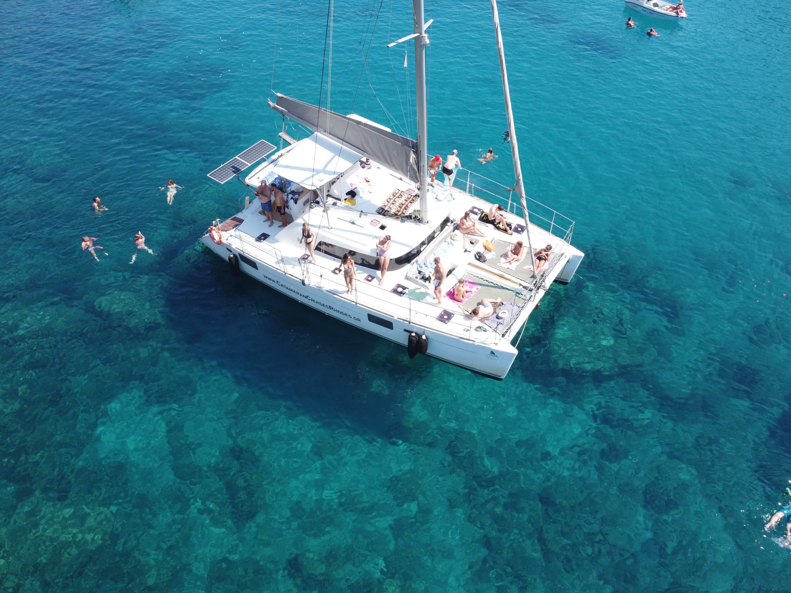 Aerial of catamaran anchored in clear Rhodes sea with swimmers