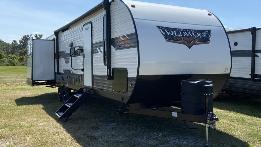Travel trailer camping on open grassy field with clear sky