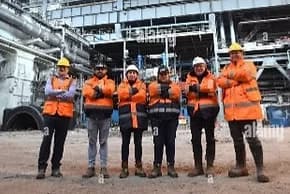 Group of industrial workers posing at outdoor plant site