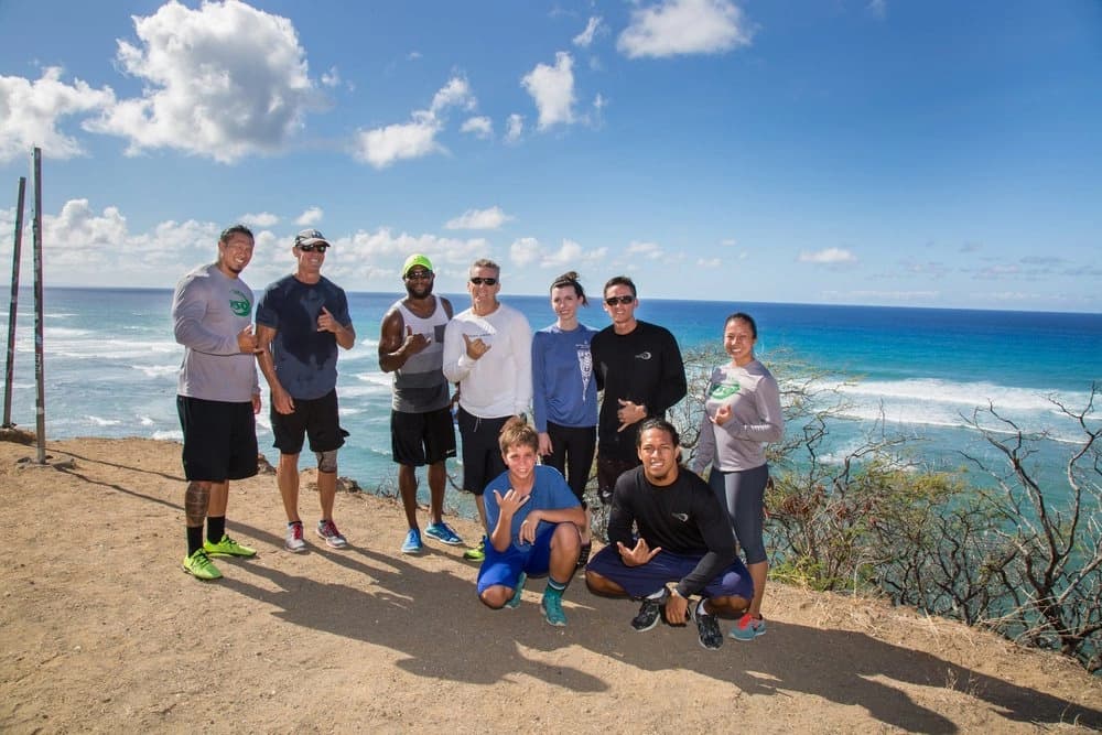 Hiking group gathered on coastal ridge trail with ocean views, Hawaii