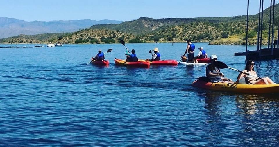 Kayakers paddling on mountain lake at calm scenic outdoor reservoir