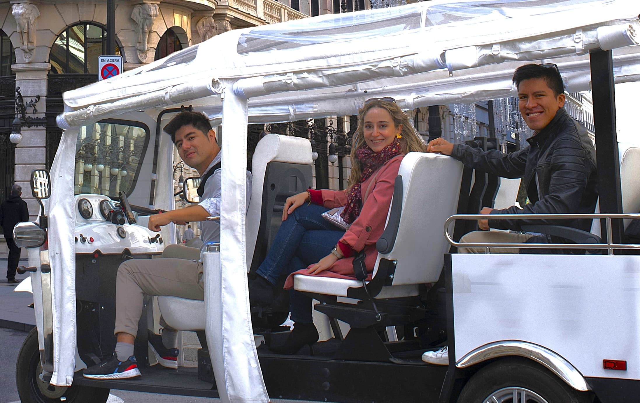 Open-air tuk-tuk ride through Madrid streets with tourists seated