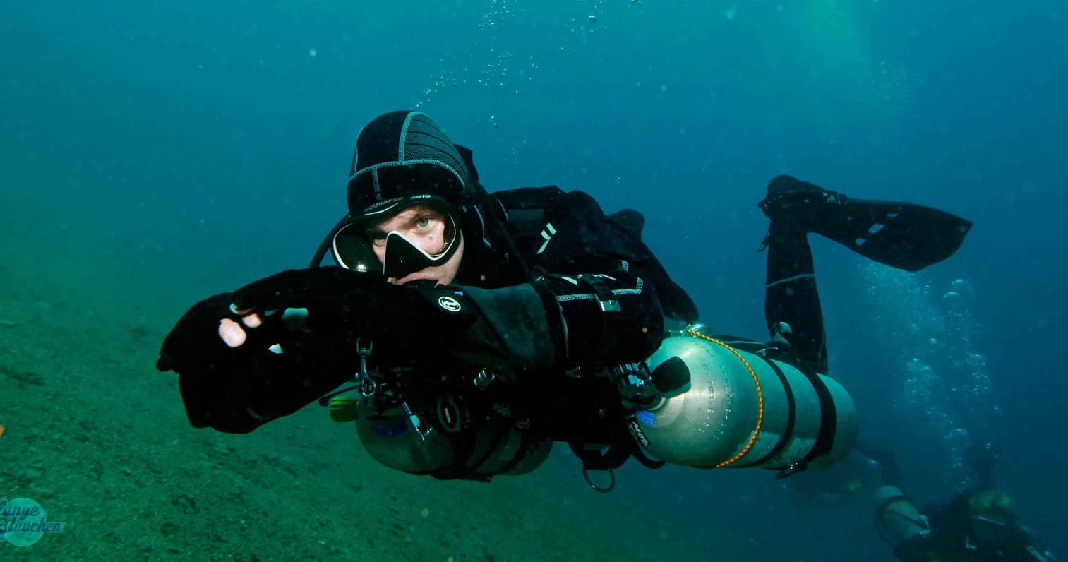 Single diver benching with cylinder exploring wreck site underwater