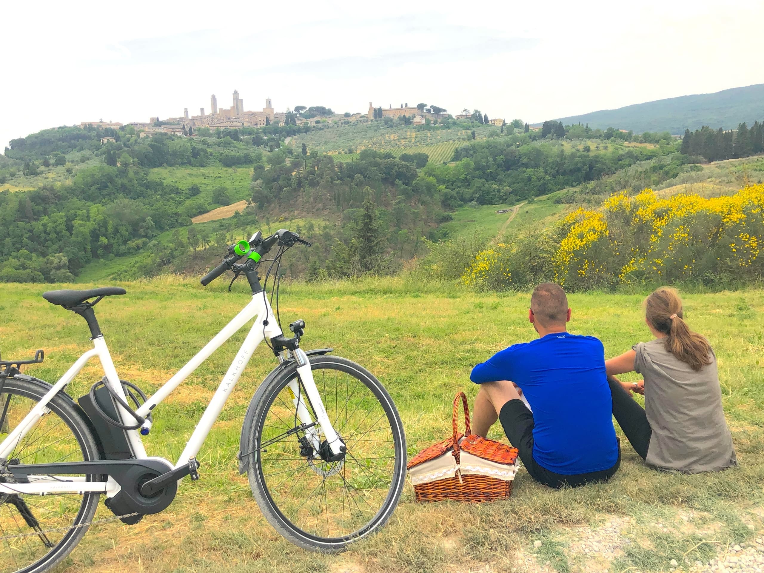 Couple biking and picnic overlooking rolling Tuscan vineyards