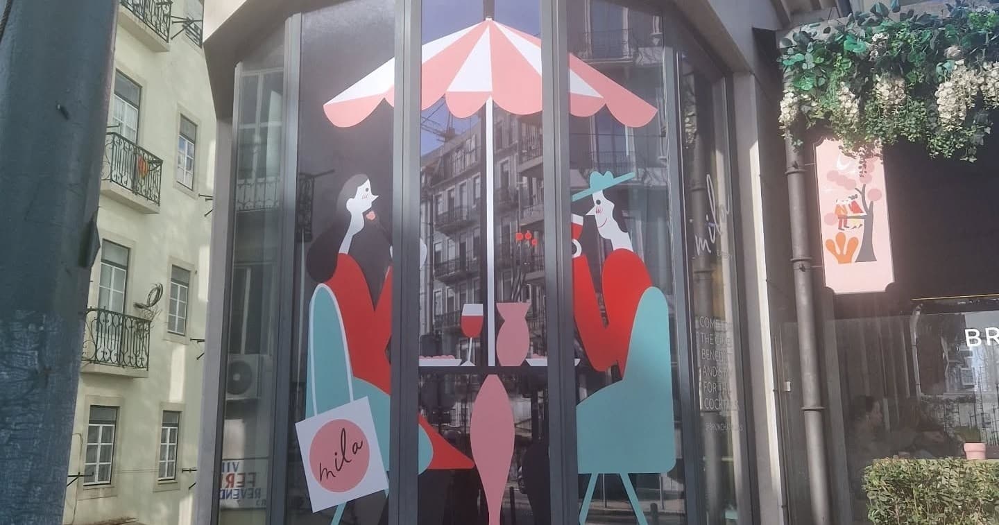 Cafe storefront window mural showing seated figures in Lisbon