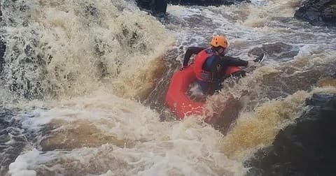 Whitewater kayaking through turbulent river rapids in forested canyon