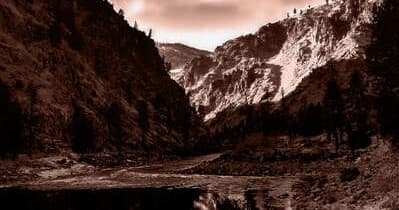 Sepia-toned mountain lake panorama with dramatic alpine peaks and trees