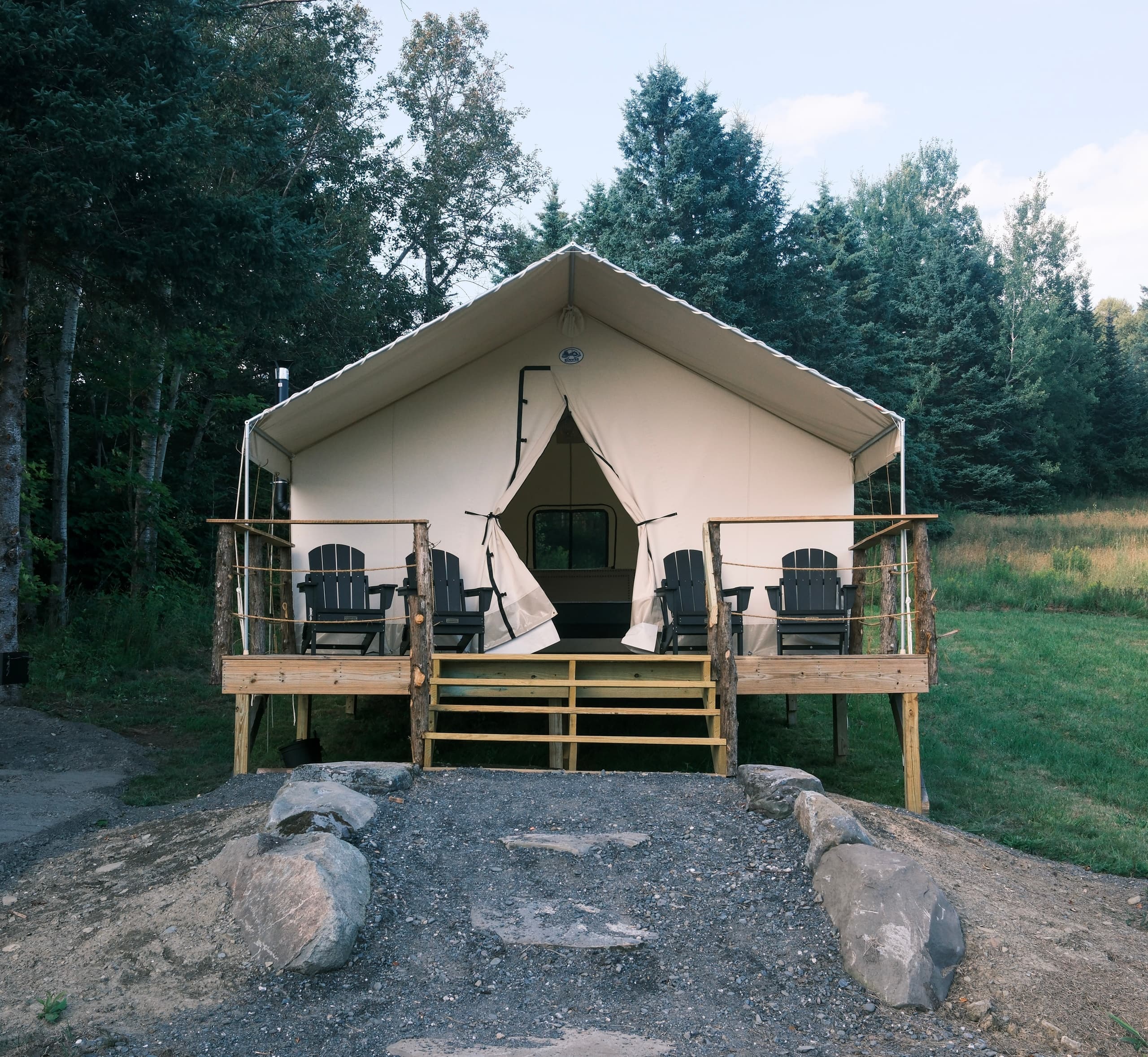 Front view of glamping tent with porch in forested campsite