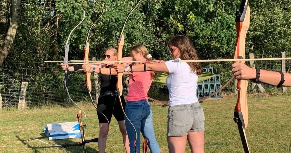 Group archery session outdoors on grass field near woods in Norderstedt