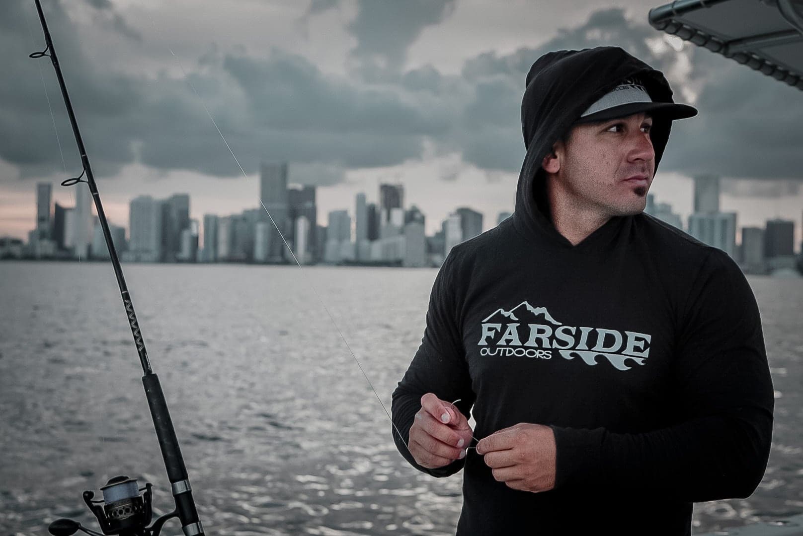 Angler fishing near city skyline from boat on cloudy day