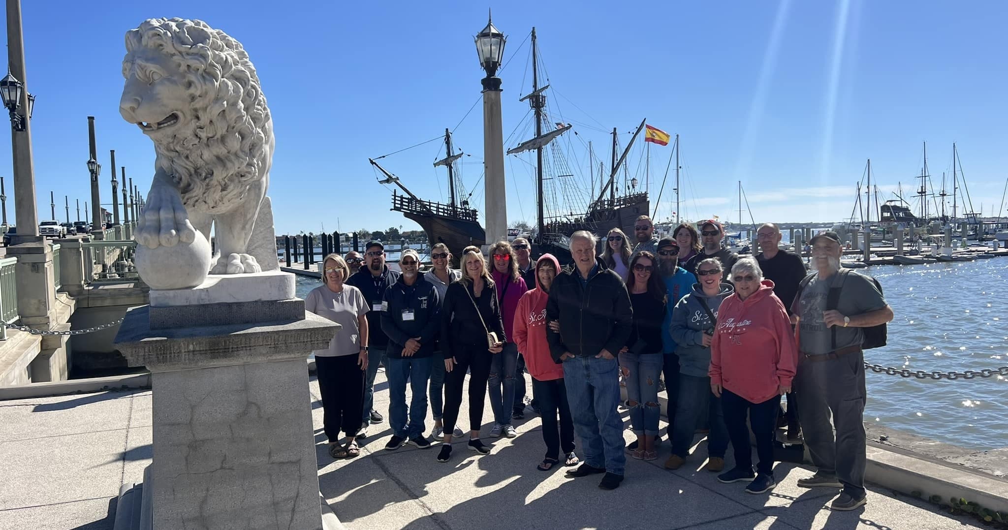 Group touring historic tall ship at sunny marina waterfront