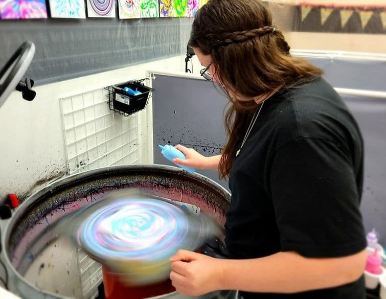 Artist creating colorful spin art on tabletop spinner machine