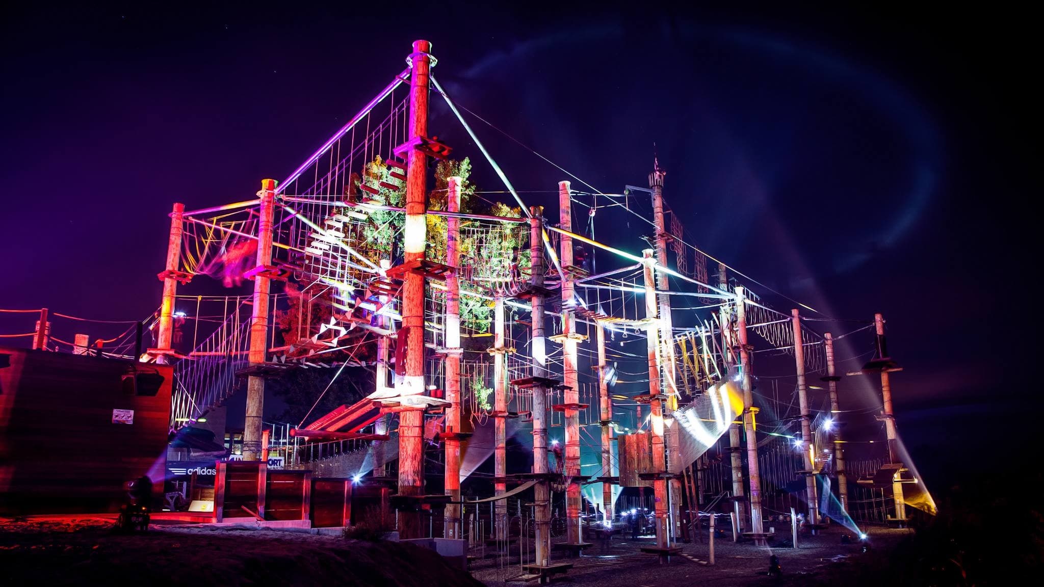 Outdoor high ropes course lit at night, climbing adventure park