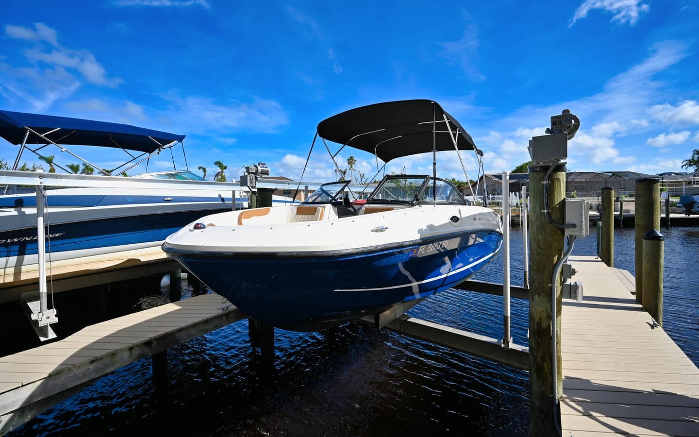 Sportboat at lift with palm trees and bright blue sky