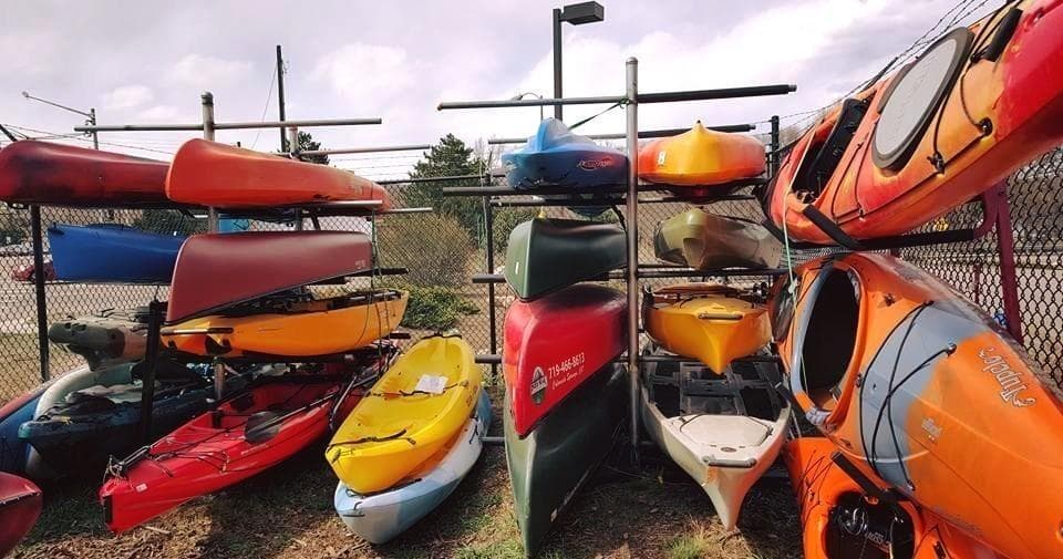Colorful kayaks stacked at rental yard showing equipment inventory