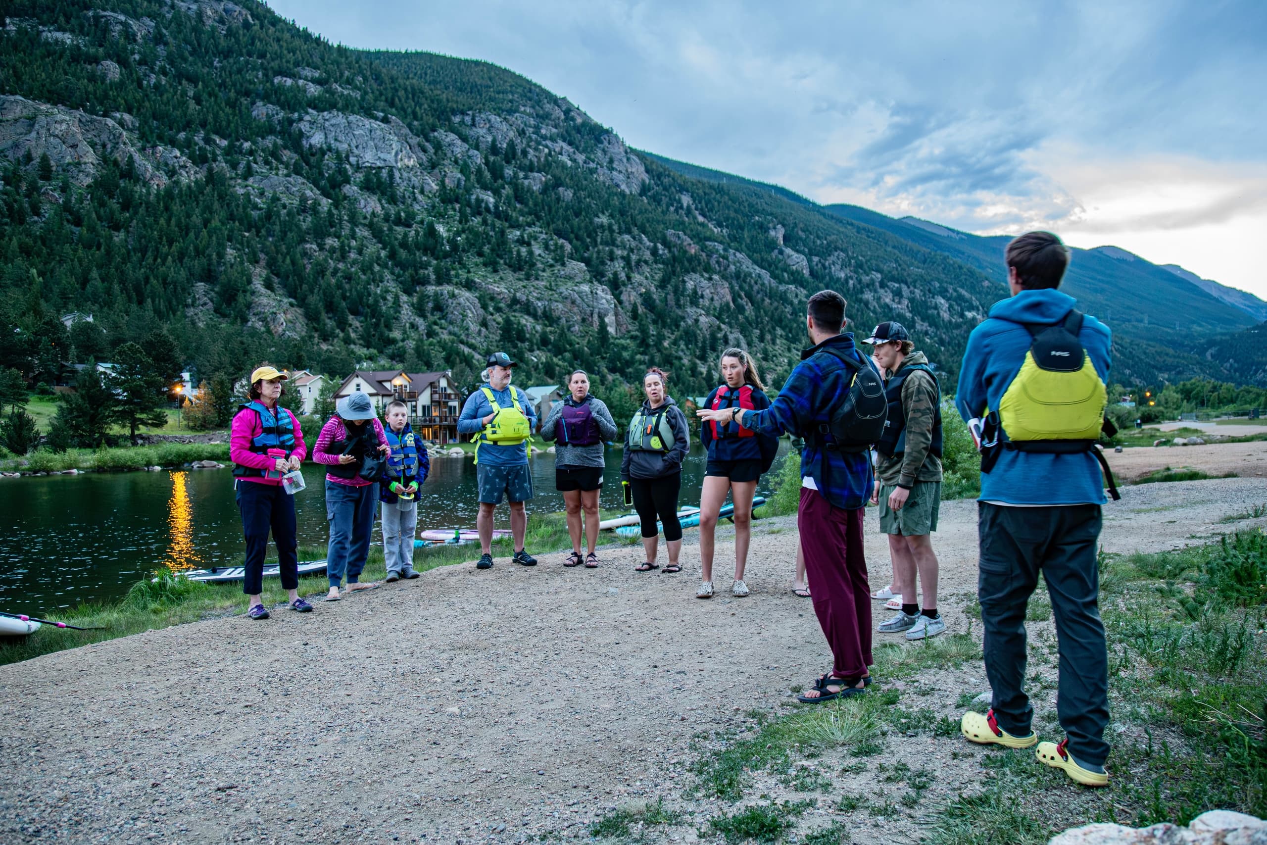 Guided lakeside hiking group beside alpine reservoir at dusk